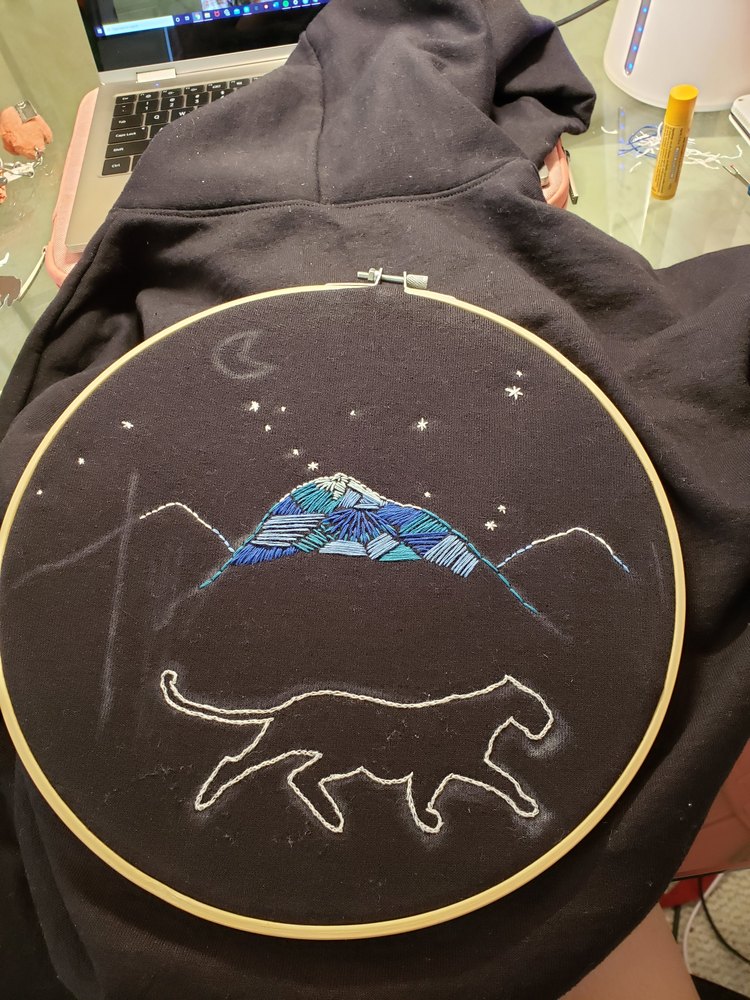 Embroidery hoop with mountain, stars, and cat outline