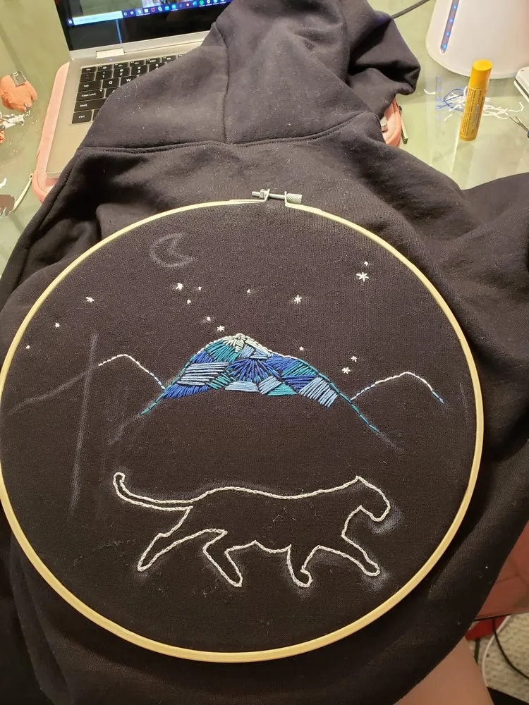Embroidery hoop with mountain, stars, and cat outline
